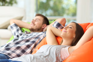 Couple or roommates relaxing lying on comfortable poufs in the living room at home