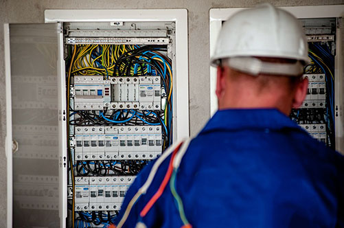 Back of electrician's head as they work on an electrical panel